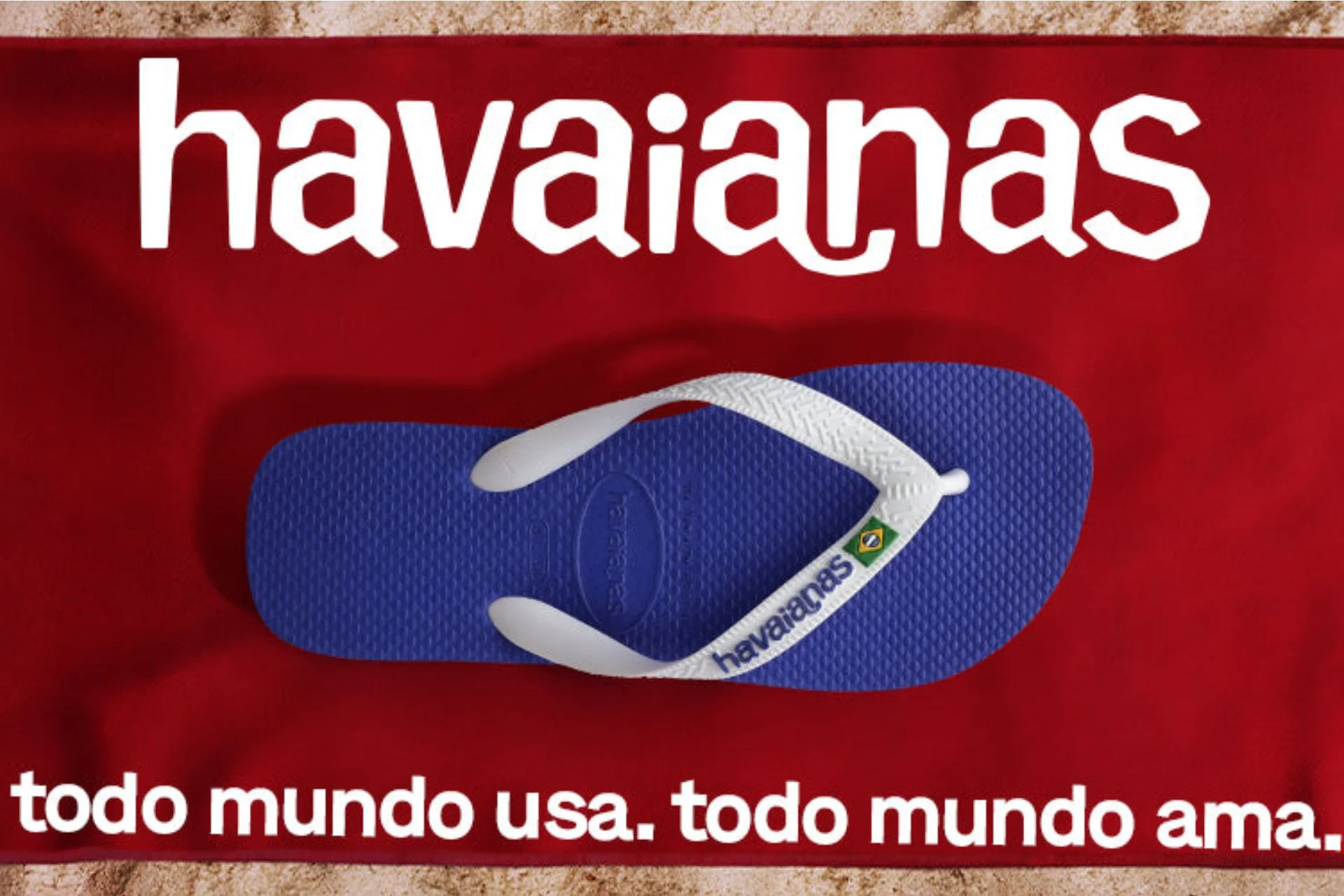 Fundo vermelho com um chinelo da marca Havaianas na cor azul com tiras brancas posicionada no centro da imagem. Na parte superior tem o logo da empresa e na parte inferior a frase 'todo mundo usa. todo mundo ama'.