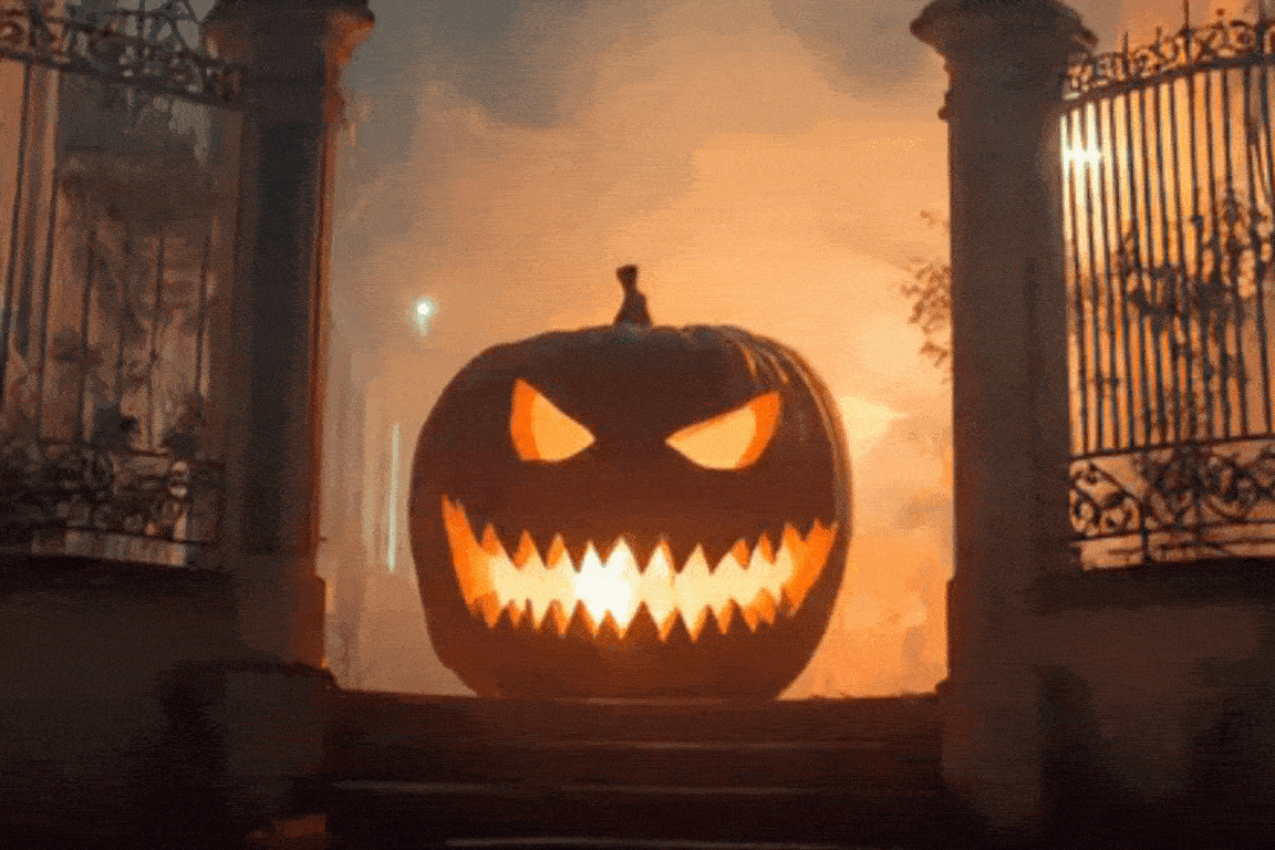 Abóbora de halloween é vista na frente de uma casa, ao fundo vemos uma paisagem sombria.